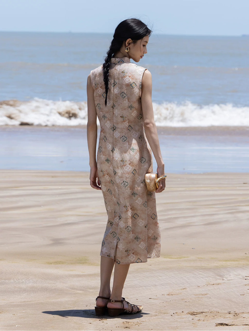 Sleeveless floral Mandarin collar midi dress in soft sand worn on a beach.
