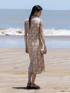Sleeveless floral Mandarin collar midi dress in soft sand worn on a beach.