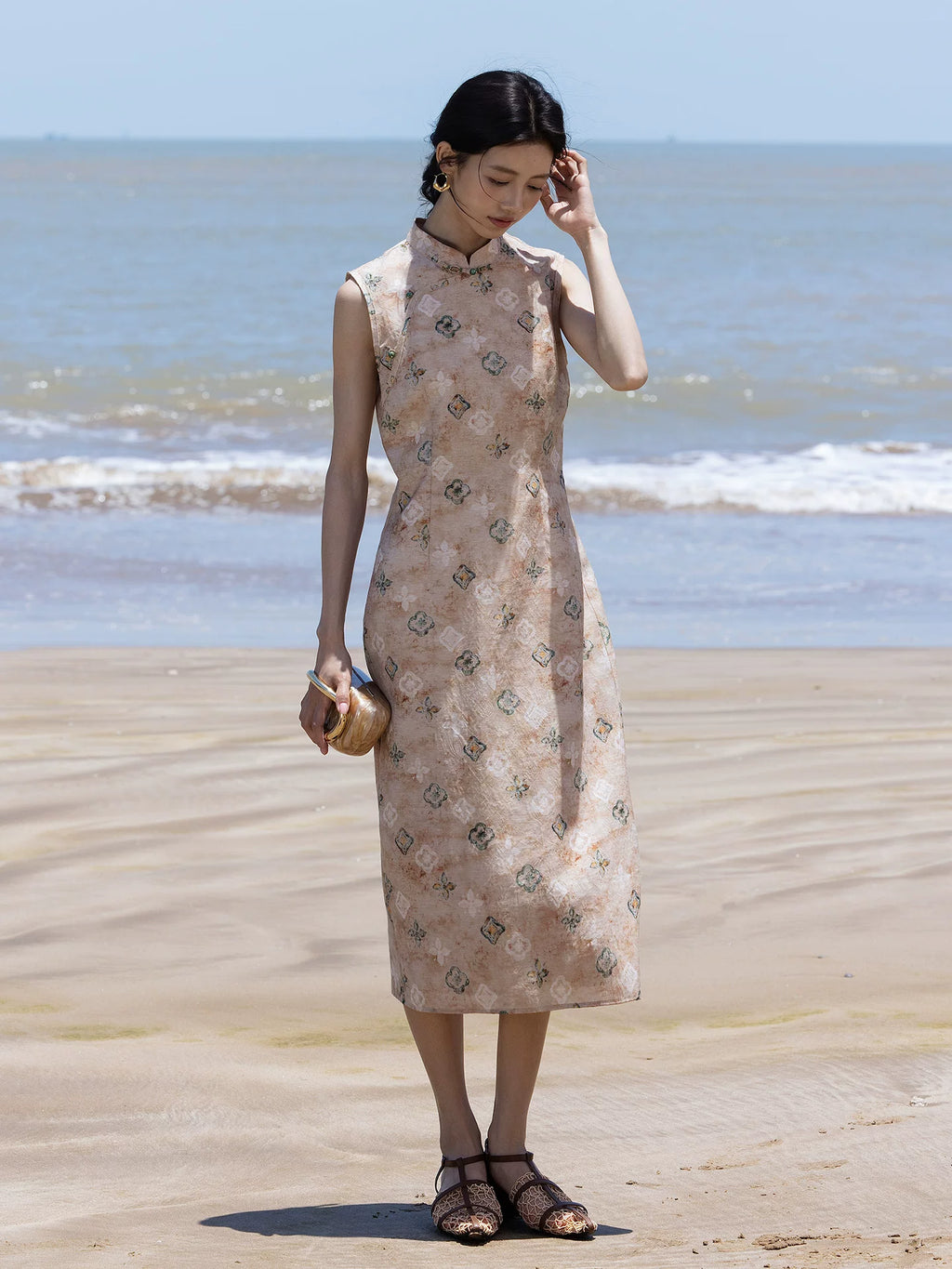 Full-length view of a sleeveless floral midi dress styled for a seaside holiday.