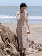 Women's floral midi dress with Mandarin collar standing on coastal rocks.