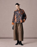 Woman wearing an antique bronze goldfish jacquard jacket with wide-leg brown trousers