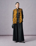 Woman wearing an antique gold floral jacquard Mandarin collar vest with black wide-leg trousers