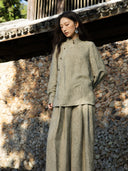 Model wearing an antique sage floral jacquard shirt with a stand collar and asymmetric buttons, paired with matching wide-leg trousers.