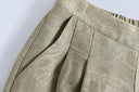 Close-up of antique sage jacquard trousers showing front pleats, the waistband and gathering along the elasticated back section.