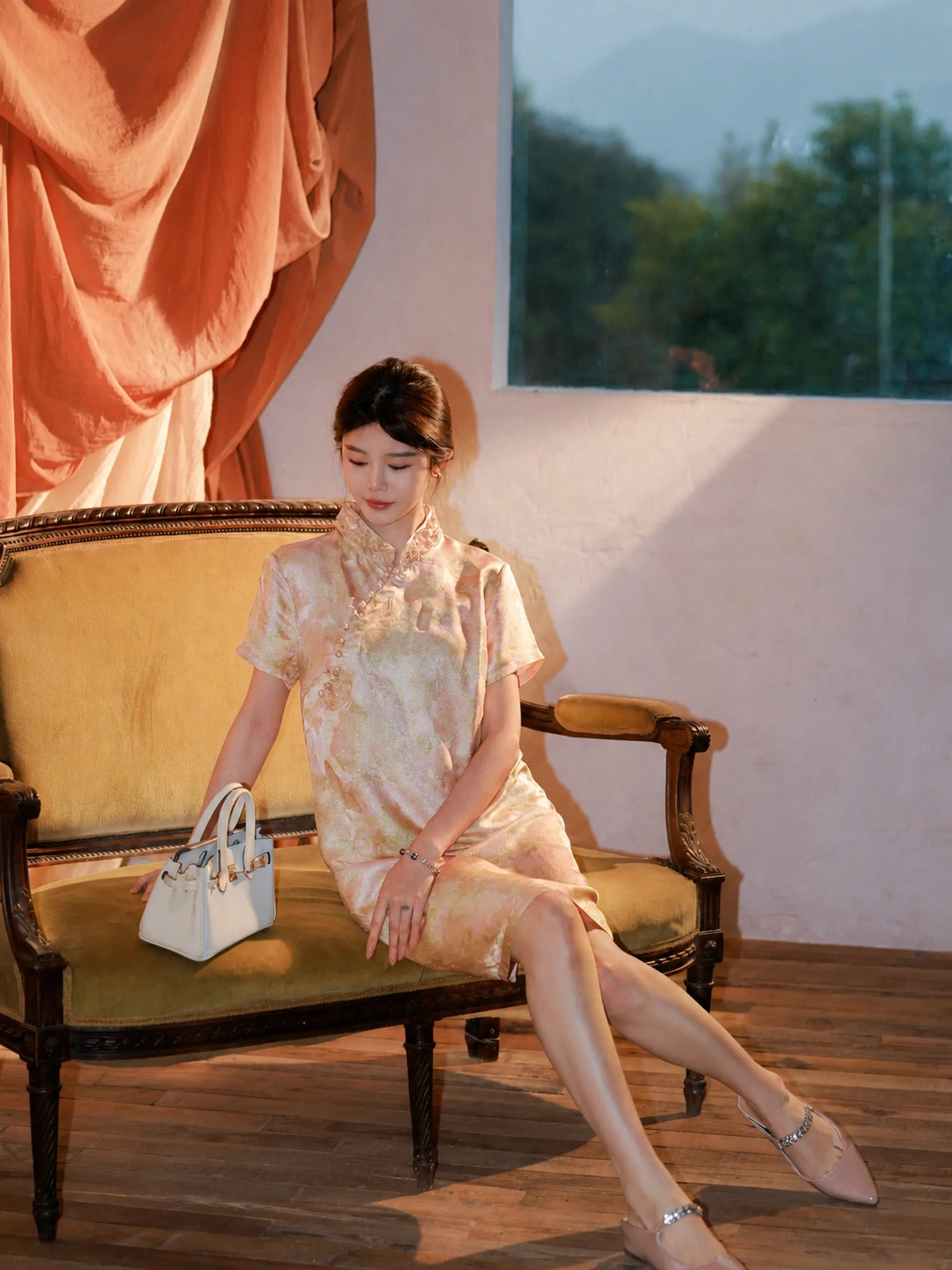 Model wearing an apricot 100% mulberry silk Chinese-inspired dress while seated