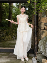 Side view of apricot cream pleated wide-leg pants with a layered lace hem, styled with a lace top and holding a fan, highlighting the relaxed and elegant fit.