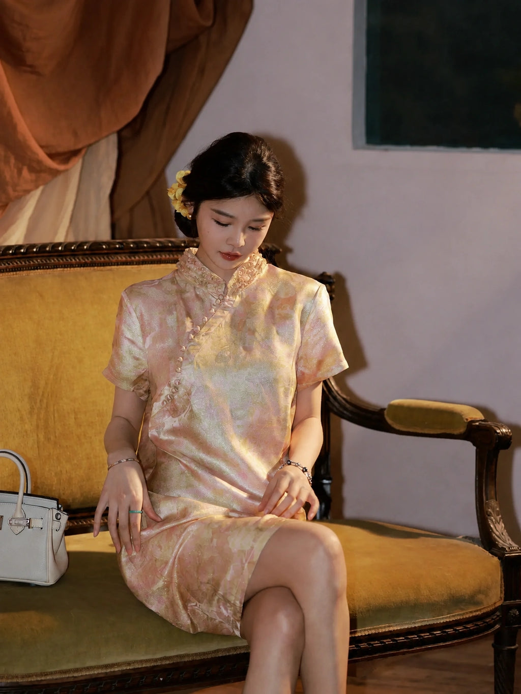 Model seated in an apricot qipao-inspired silk dress with a fitted A-line silhouette