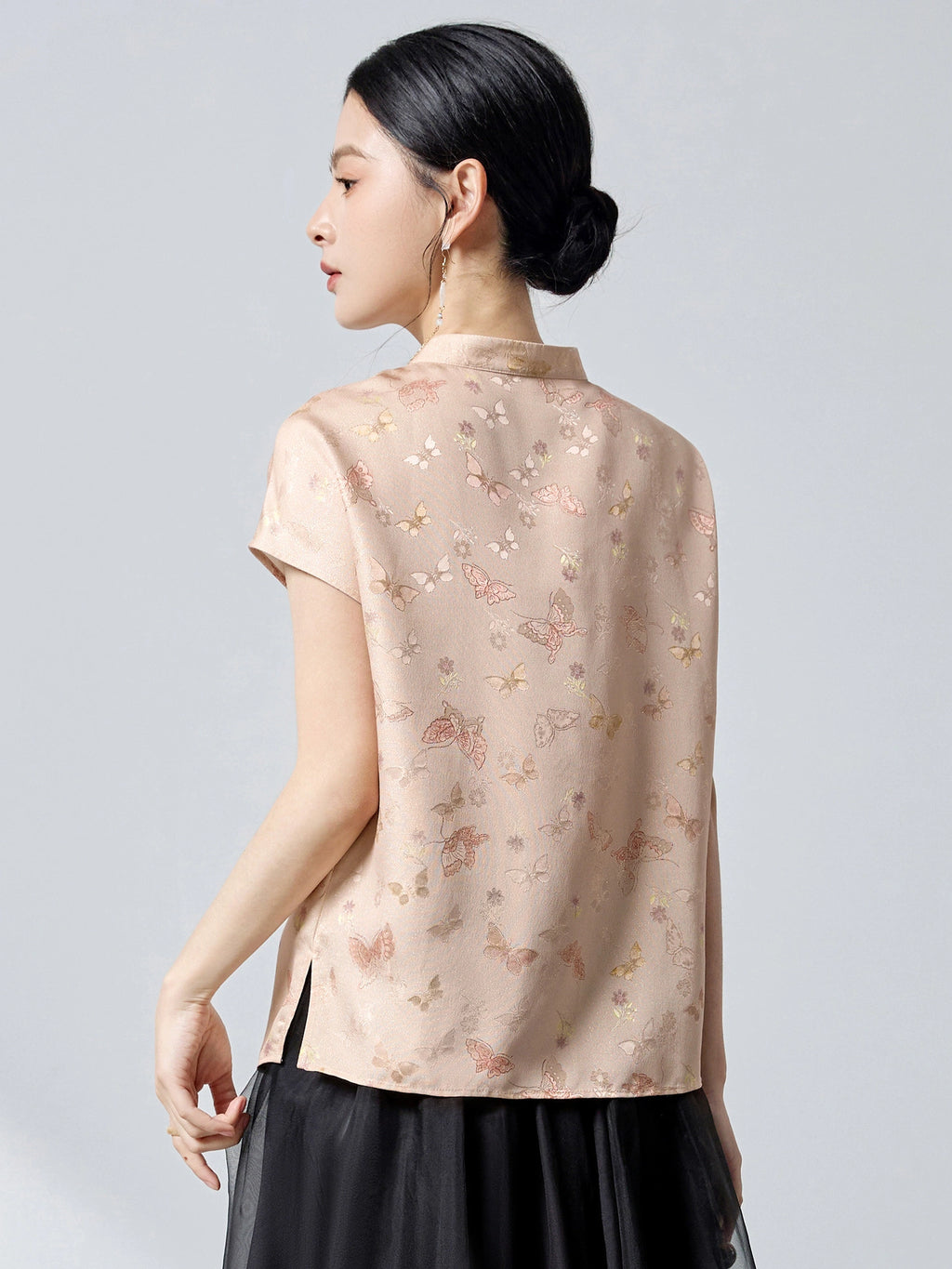 Back view of an apricot mulberry silk top with a stand collar, butterfly jacquard pattern, and a relaxed A-line fit, showcasing the 23 momme luxury fabric.