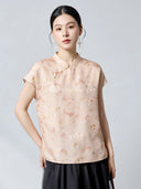 Model wearing an apricot 94% mulberry silk top with a stand collar and butterfly jacquard pattern, styled with a black skirt, featuring traditional frog buttons.