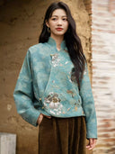 Model wearing the Baishi teal jacket, showing its stand collar, curved front and floral bead and sequin embroidery.