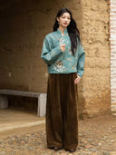 Model holding the front of the Baishi jacket, highlighting its floral embellishments and short silhouette.