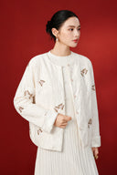 Angled front view of the pink jacket, showing the round neckline, textured surface and butterfly embellishments.