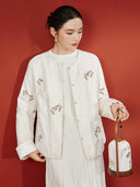 Close view of a model wearing the beige jacket, showing butterfly embroidery, front loops and contrasting fabric textures.