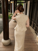Back view of a beige Cheongsam set featuring a sleeveless top and midi skirt with scalloped lace trim, styled with a hair bun.