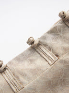 Close-up of traditional frog-button closures and geometric jacquard fabric on the beige Chinese-style vest.