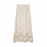 Flat lay of a beige midi skirt with floral embroidery and a scalloped lace hem, lined with 100% polyester.