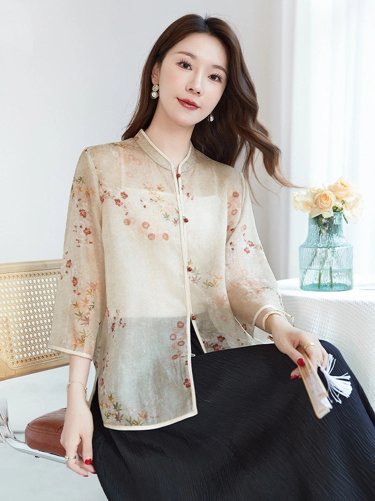 Sitting model wearing a beige silk printed shirt, showcasing the relaxed A-line silhouette and breathable, sheer fabric texture.