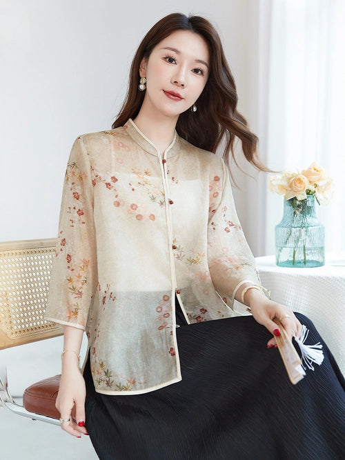 Sitting model wearing a beige silk printed shirt, showcasing the relaxed A-line silhouette and breathable, sheer fabric texture.