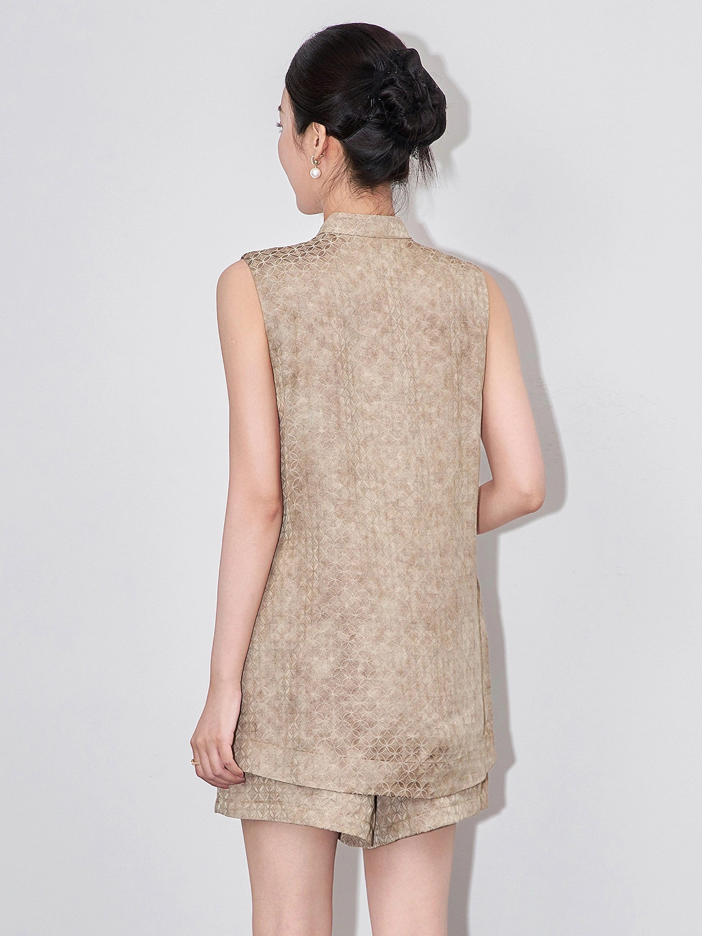 Back view of a model wearing the beige sleeveless viscose vest and matching shorts set.