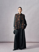 Full-length styling of a black and copper floral jacquard Mandarin vest with black wide-leg trousers
