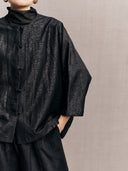 Close-up of the black crackle-pattern silk and fabric-covered front buttons