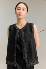 Close-up of a black silk embroidered vest top with a V-neckline, button-down front, and intricate bead and sequin detailing along the edges, crafted from 100% mulberry silk.