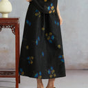 Close-up of a black mulberry silk A-line midi skirt featuring blue and gold ginkgo-leaf prints.