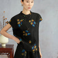 Model wearing a black mulberry silk top with multicolor ginkgo leaves, cap sleeves and Chinese-style button closures.