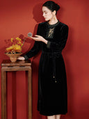 Model wearing the black embroidered dress beside an autumn flower arrangement