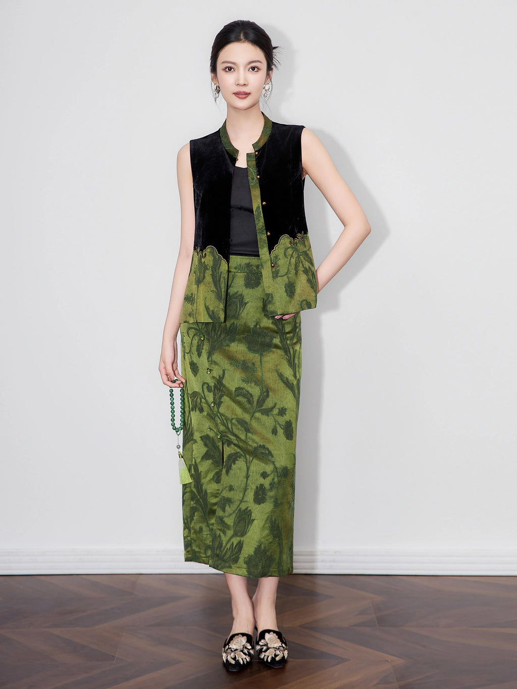 Model wearing a black silk-base velvet vest with green floral jacquard panels, Mandarin collar and gold-tone buttons.