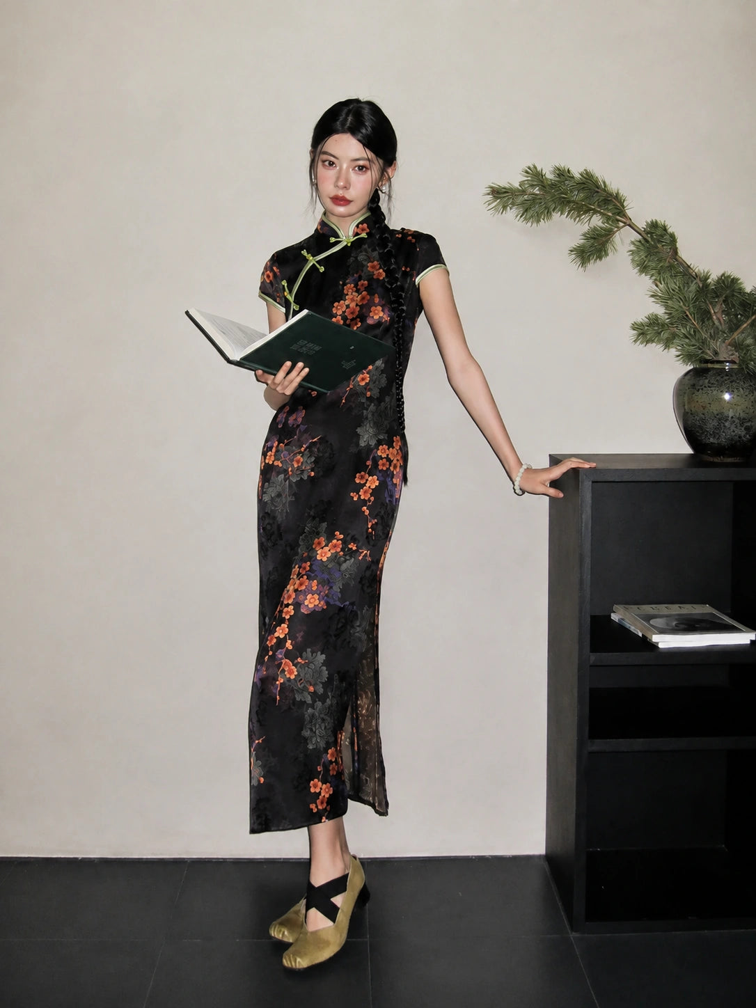 Full-body look of a black jacquard modified long qipao with diagonal placket, floral pattern, and slim elegant silhouette.