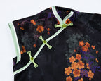 Close-up of the diagonal placket on a black jacquard qipao with pale green trim and traditional knot buttons.