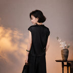 Back view of a relaxed black mulberry silk blouse with cap sleeves, lace collar and button detail