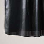 Close-up of the subtle tonal texture, sheen and lightweight hem of the black silk blouse