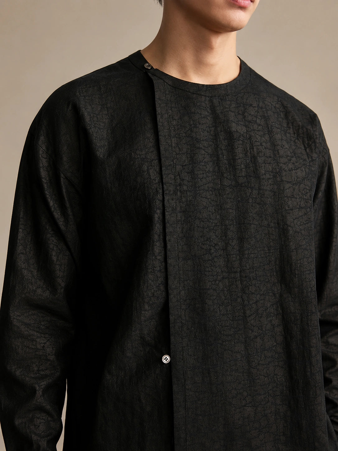 Close-up of the textured 100% mulberry silk fabric on a black designer shirt with concealed button placket.