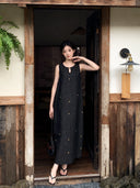 Woman wearing a black mulberry silk sleeveless maxi dress with star embroidery for summer elegance