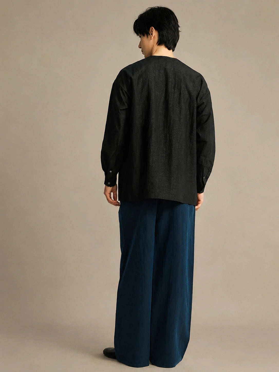 Back view of a relaxed-fit black mulberry silk unisex shirt with clean minimalist tailoring.