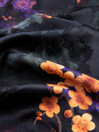 Fabric detail of black rayon jacquard with tonal floral texture and orange blossom pattern.