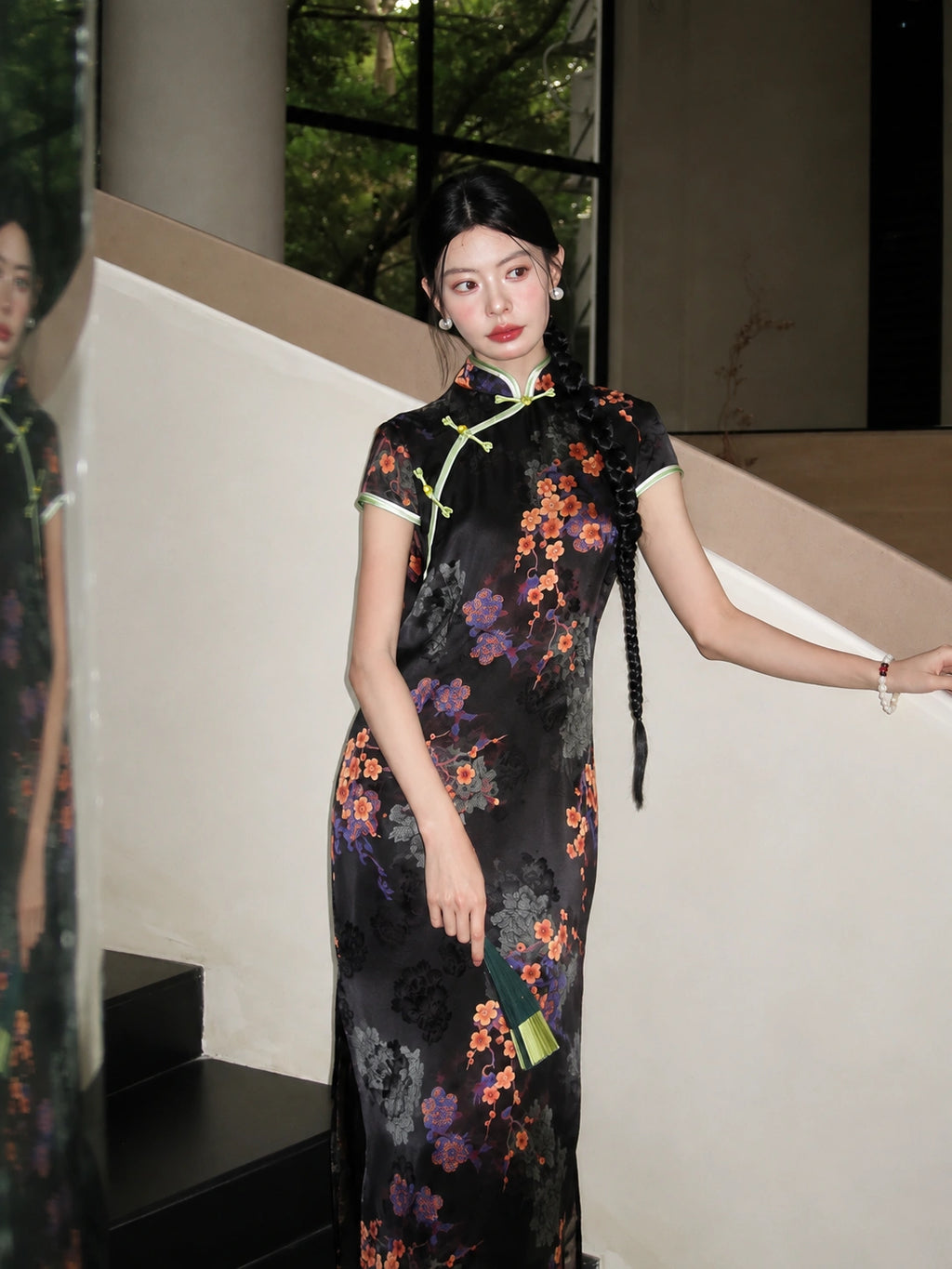 Black rayon jacquard long qipao with diagonal front closure, floral print, cap sleeves, and green contrast trim.