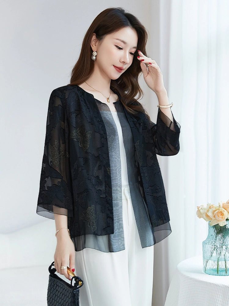 Side view of a model wearing a black silk cardigan with a relaxed fit, holding a woven bag, showcasing the flowy drape and sheer texture.