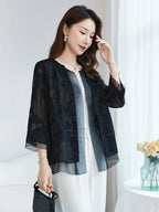 Side view of a model wearing a black silk cardigan with a relaxed fit, holding a woven bag, showcasing the flowy drape and sheer texture.