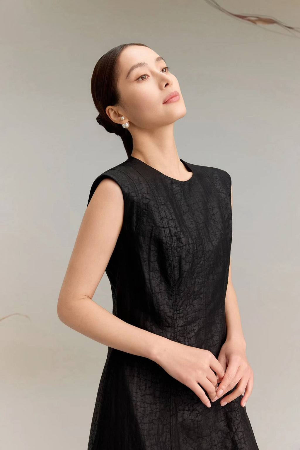 Close-up of a black silk dress with a round neckline and textured jacquard finish, highlighting the luxurious sheen and soft drape of the premium silk fabric.