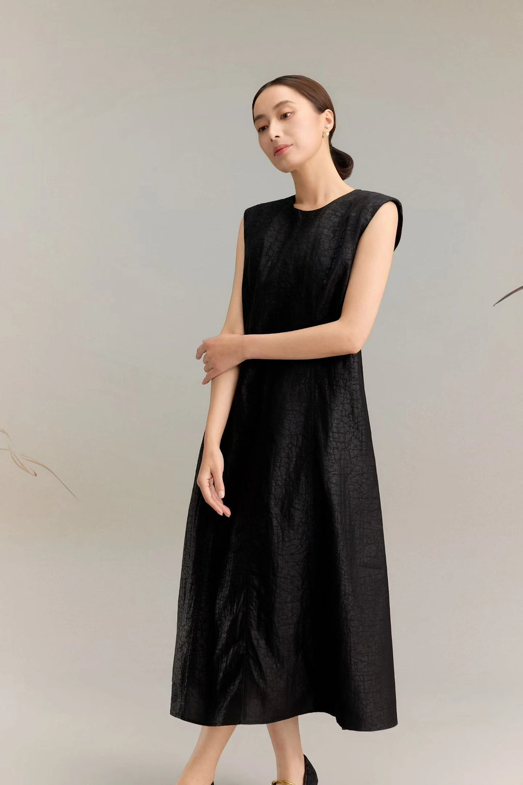 Side view of a black silk sleeveless A-line dress with a round neckline, crafted from 100% mulberry silk, featuring a relaxed fit and midi length.
