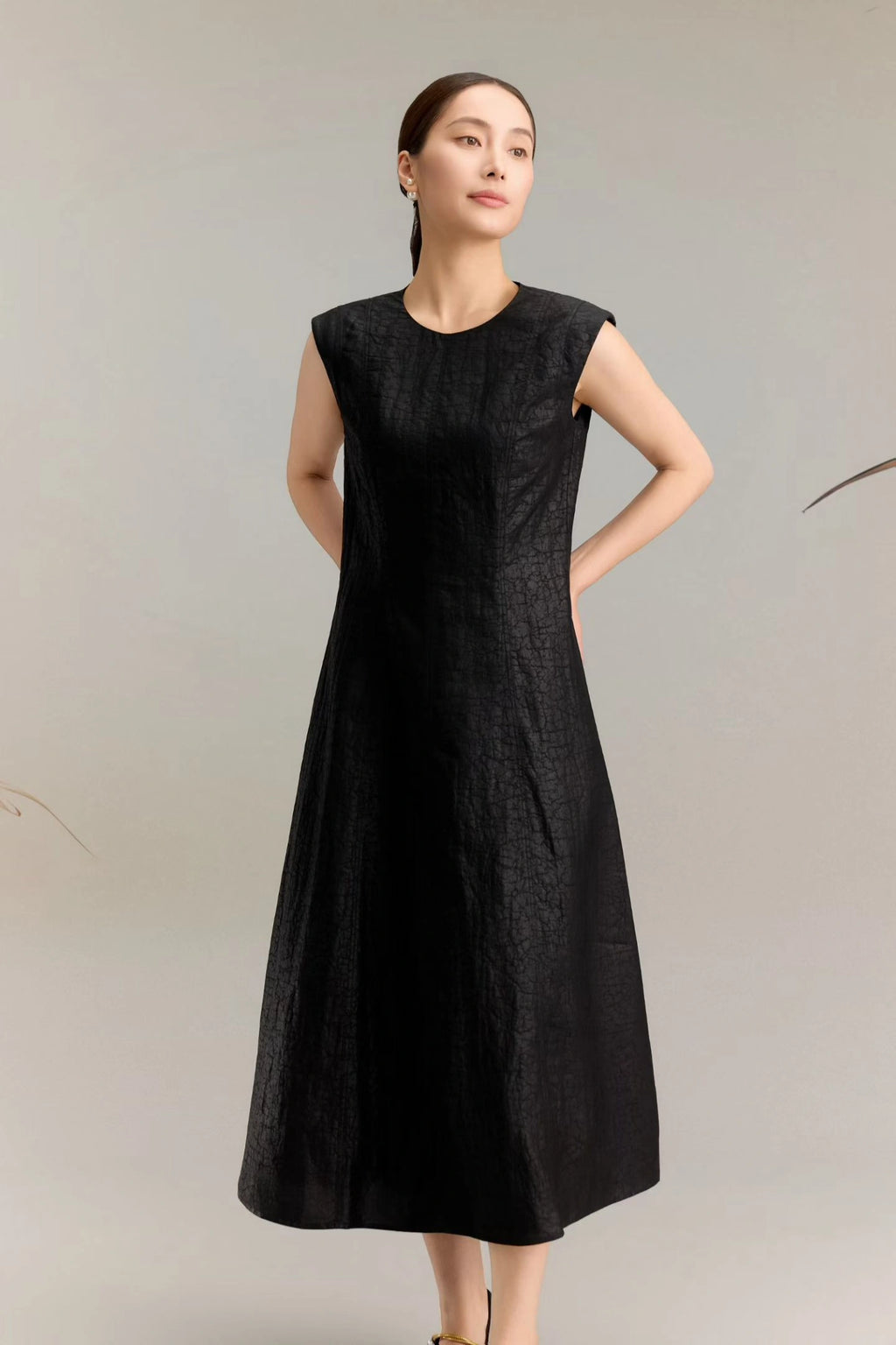 Front view of a women's black silk midi dress with a sleeveless design and subtle textured fabric, showcasing the elegant drape of the 100% silk material.