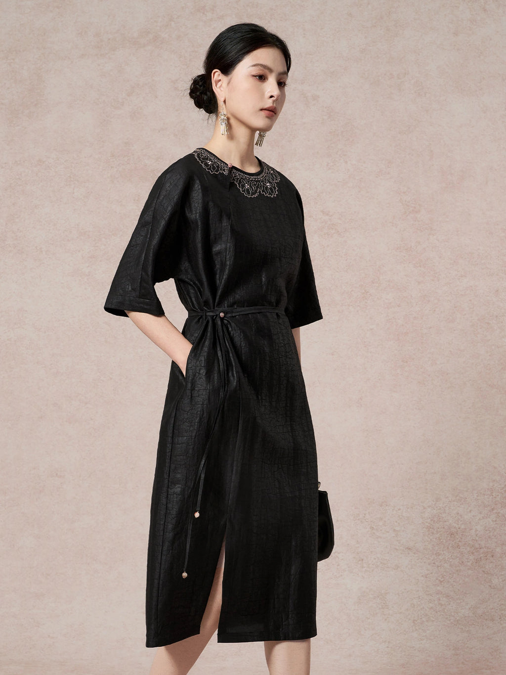 Side view of a black silk dress with a round neckline, side tie waist, and short sleeves, highlighting the comfortable and flattering fit.