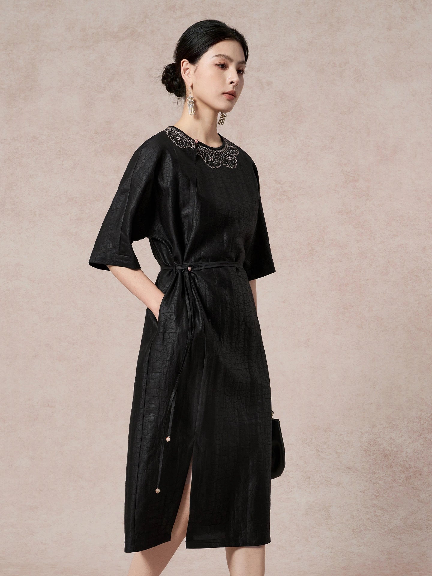 Side view of a black silk dress with a round neckline, side tie waist, and short sleeves, highlighting the comfortable and flattering fit.