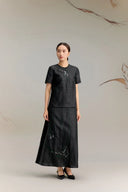 Full body shot of a black silk co-ord set featuring a short sleeve top with abstract embroidery and a matching A-line skirt with embroidered hem, crafted from 100% silk.