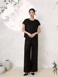 Full body shot of a black silk co-ord set featuring a round neck short sleeve blouse with scattered copper-gold floral embroidery, paired with matching wide-leg palazzo trousers, crafted from 100% mulberry silk.