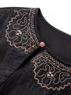 Close-up of the intricate scalloped embroidery on the neckline of a black 100% mulberry silk dress, showing the fine craftsmanship and bead details.