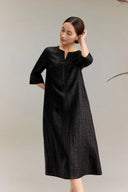 Side view of a black silk dress with three-quarter sleeves and delicate embroidery detailing on the bodice and sleeve cuffs, showcasing the luxurious drape and subtle textured jacquard finish of 100% silk.